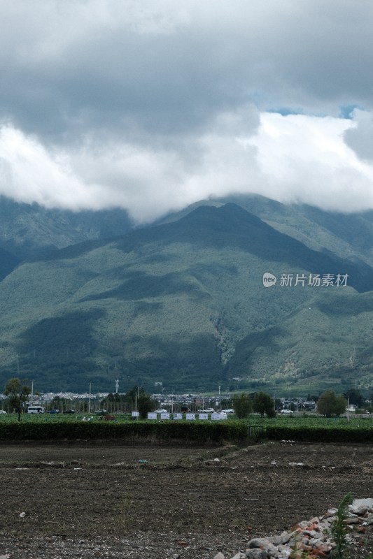 阴云下的青山远景及山脚下的土地