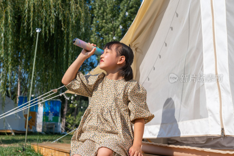 一个女孩坐在帐篷外玩耍