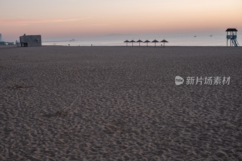 空旷沙滩上的遮阳伞与海边瞭望台