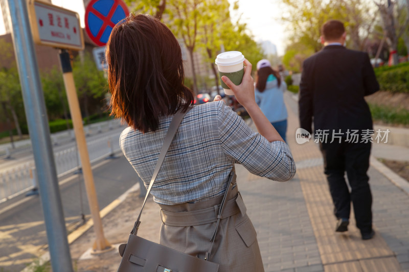 青年女人拿着饮料走在马路上