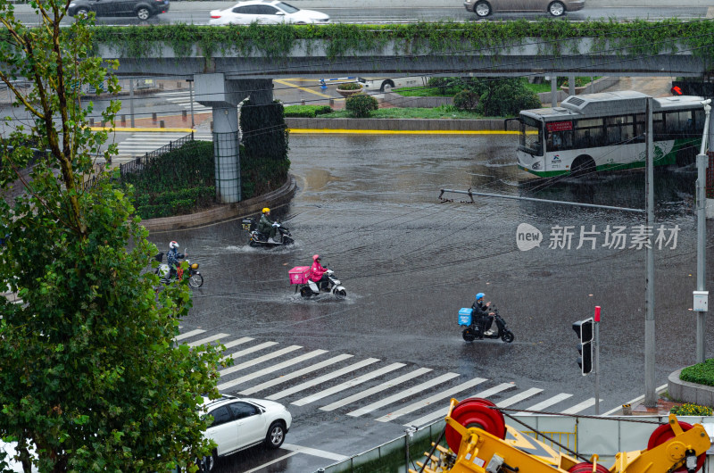 大雨中送外卖的几位外卖员经过路口