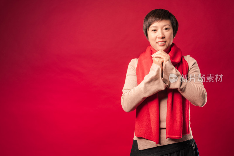 站在红色背景前作揖的中国年轻女性