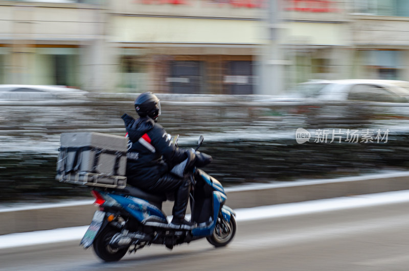 冬季马路上正骑车送餐的外卖员