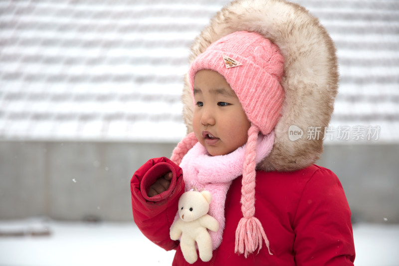 穿的厚厚实实站在风雪中的小女孩