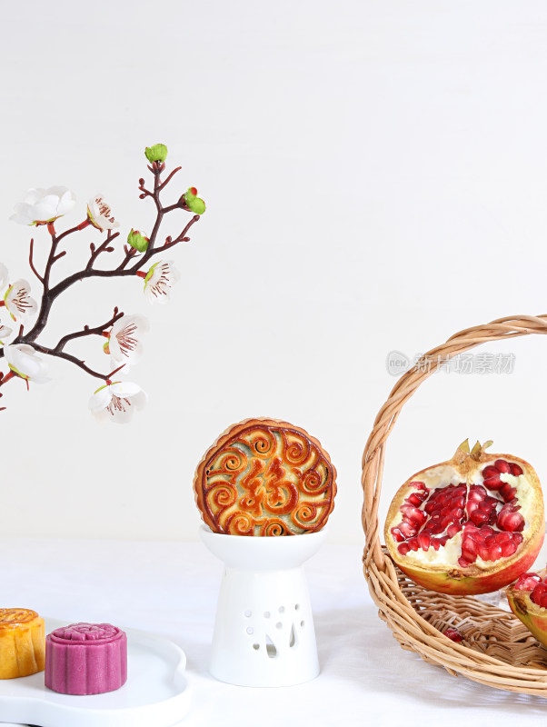 白色桌面上的中秋节月饼、茶和水果石榴