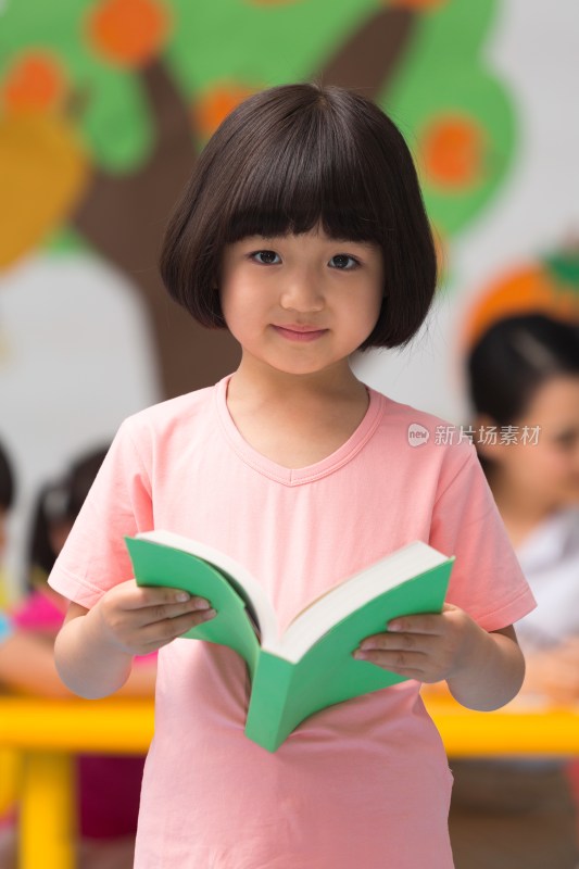 幼儿园儿童拿着书本站立微笑
