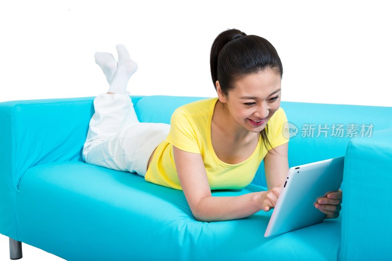 棚拍年轻女人趴在沙发上玩平板电脑