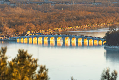 北京颐和园黄昏下金光璀璨的十七孔桥全景