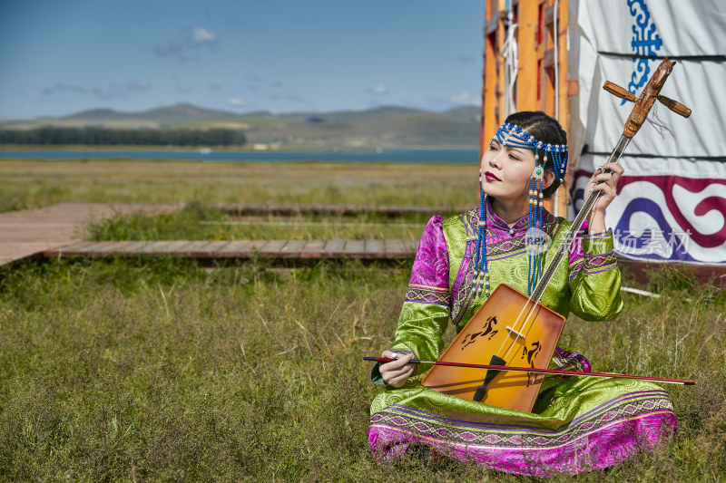 蒙古包前穿蒙古族服饰拉马头琴的蒙族女乐手