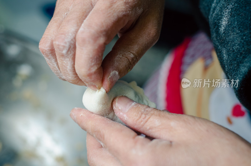 正在包饺子的母亲的手部特写