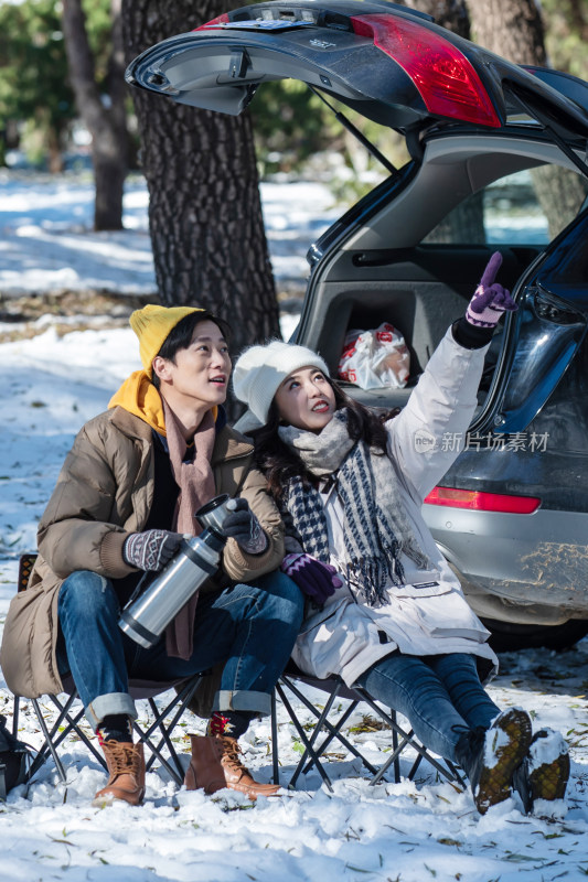 坐在汽车旁的青年夫妇