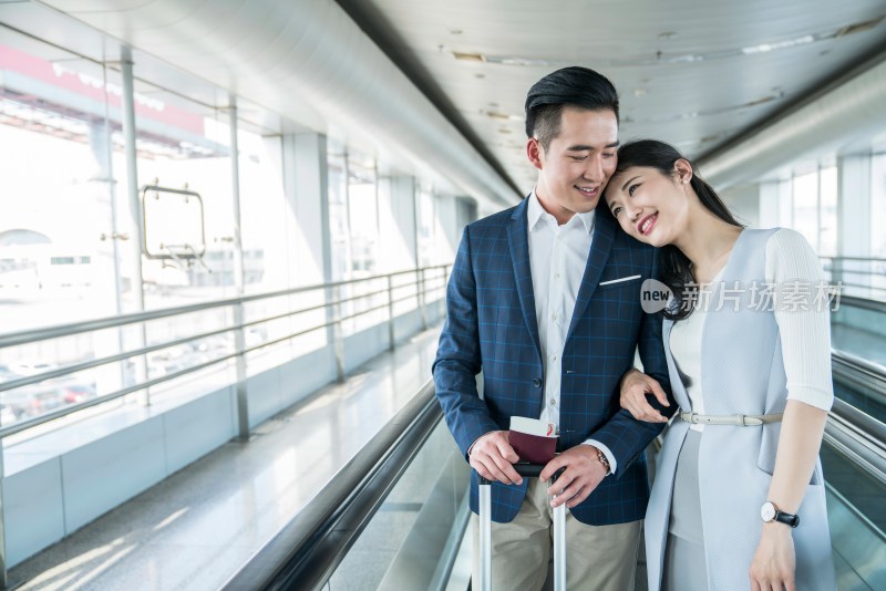 年轻情侣在机场乘坐移动电梯