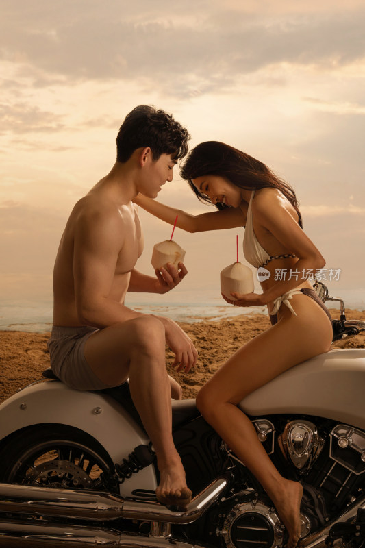 青年情侣在沙滩上喝椰汁