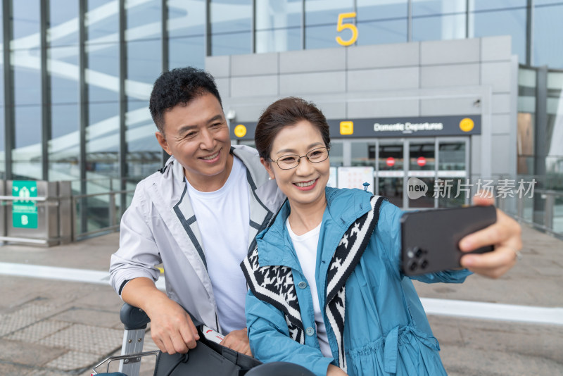 快乐的老年夫妇在机场用手机自拍