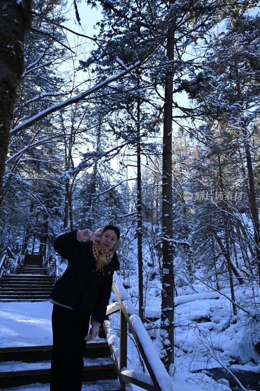 女子在积雪森林的楼梯处摆姿势拍照