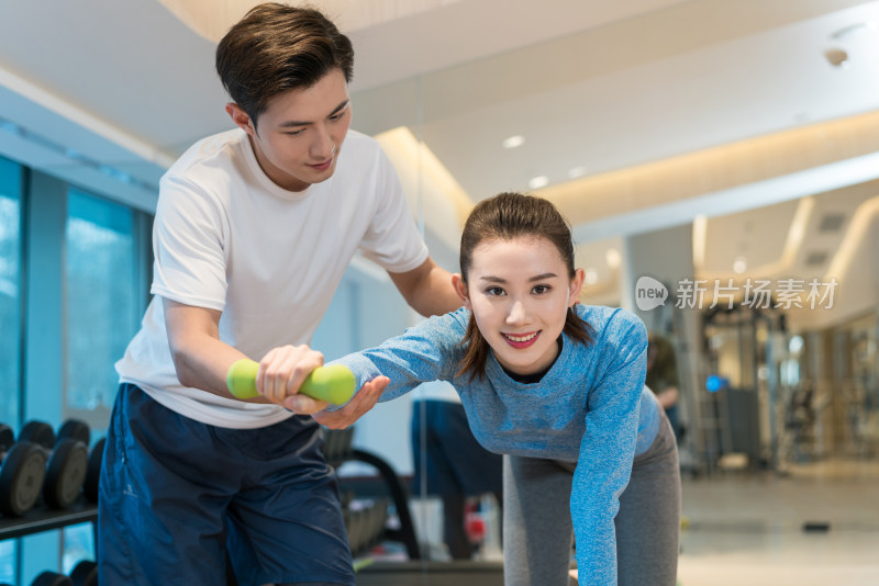 年轻女子在私教的指导下健身