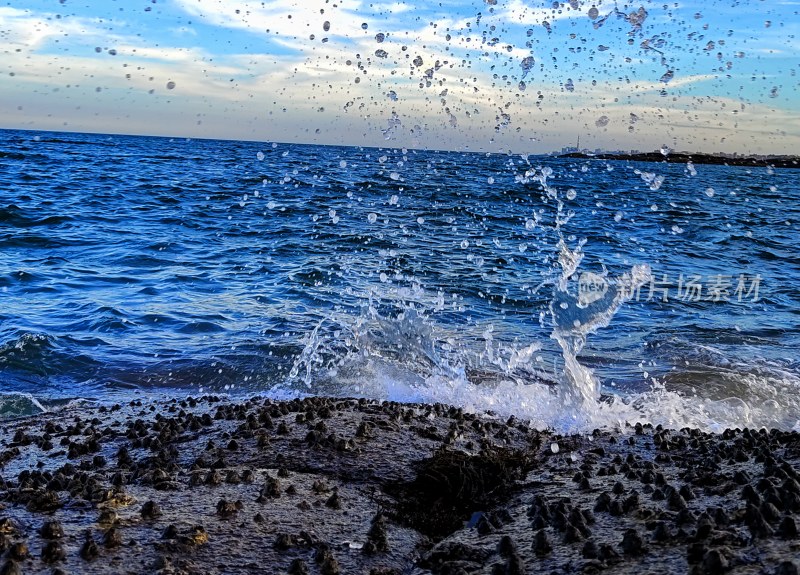 海边礁石上的海浪拍打溅起水花瞬间