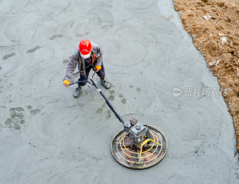 建筑工地上，工人使用路面抹平机平整路面