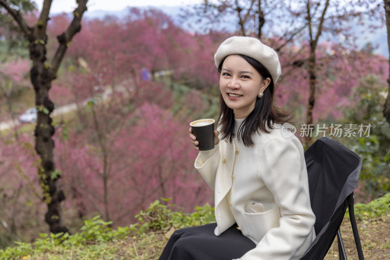 在樱花树下喝咖啡的年轻美女唯美肖像