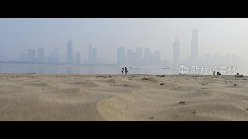 沙滩上的人眺望远处的城市建筑群