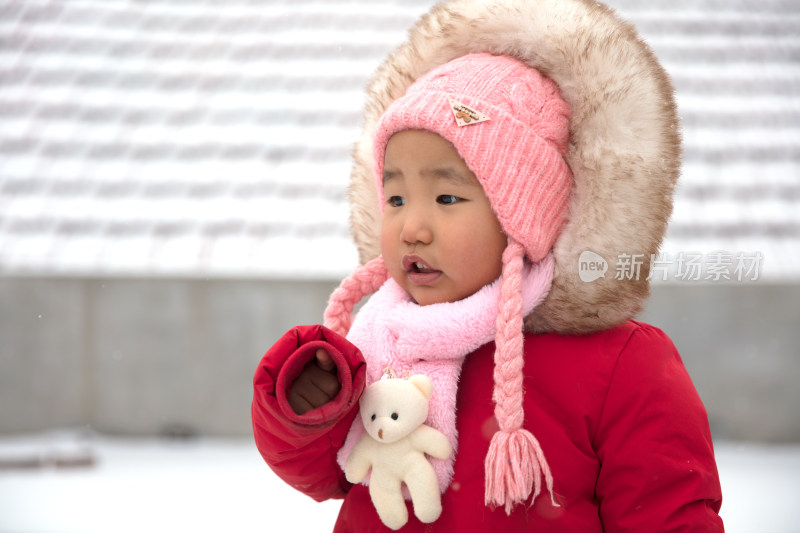 穿的厚厚实实站在风雪中的小女孩