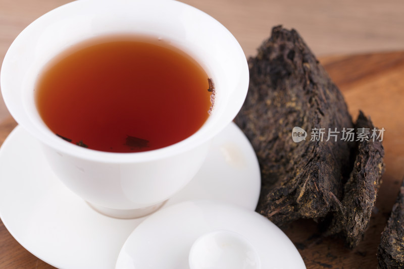 红润的茯茶茶汤在盖碗里及旁边的茶块