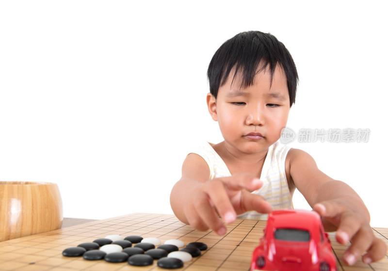 中国小女孩在放着棋子的棋盘上玩小汽车玩具