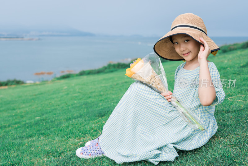 坐在山坡草地上眺望远方大海的女孩