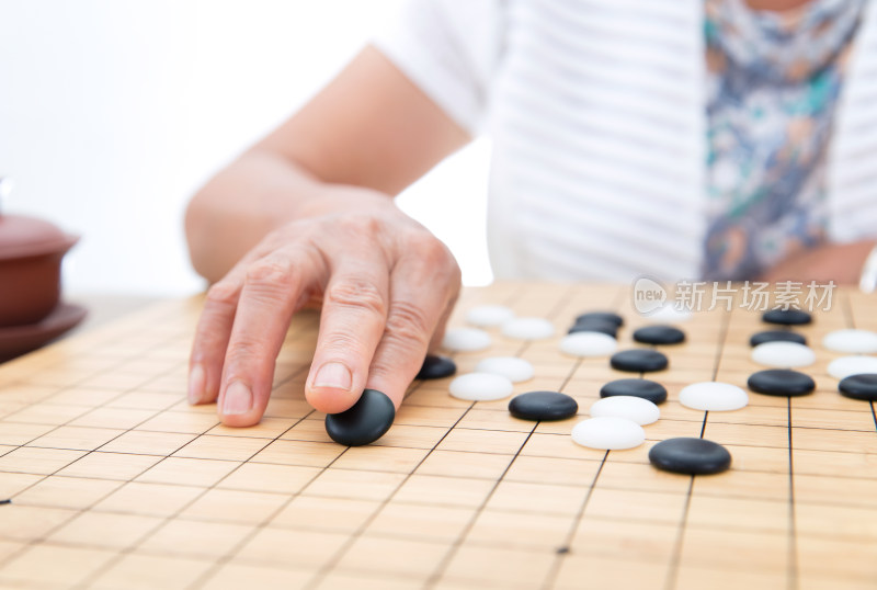 手拿黑色棋子在围棋棋盘上落子