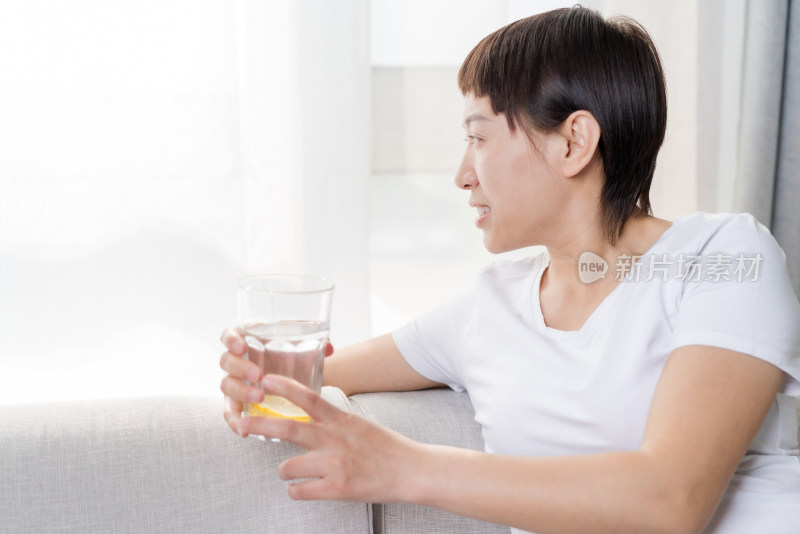 坐在沙发上喝水休息的中国女性