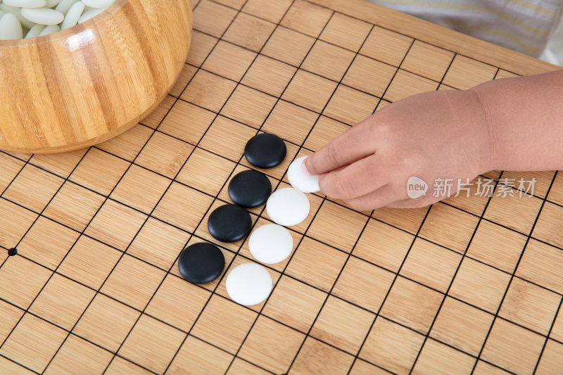 小手拿着棋子在围棋棋盘上下棋