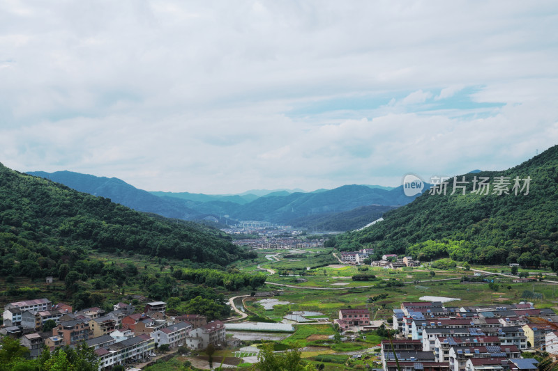 高视角俯拍蓝天白云下群山之间的农村村落