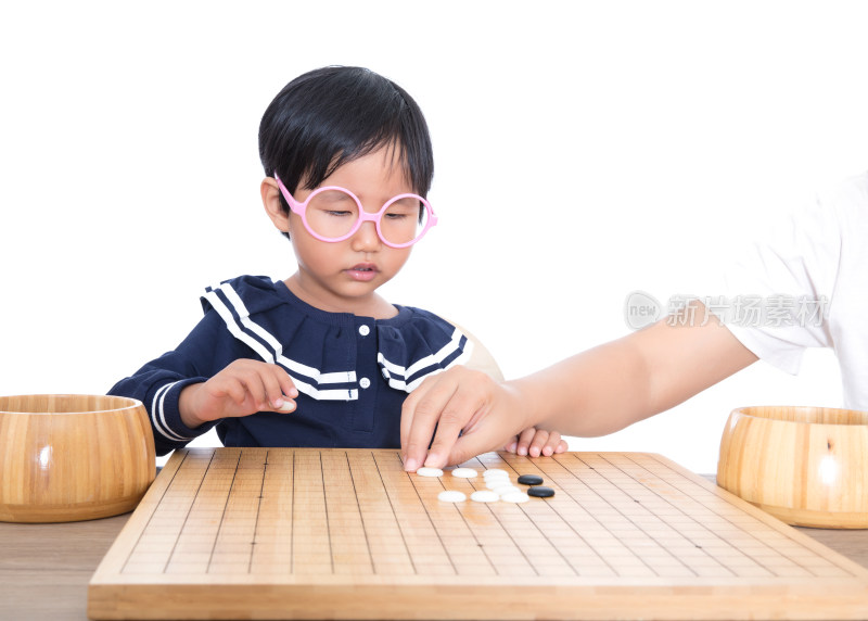 戴眼镜框的小女孩在老师的指导下学习下围棋