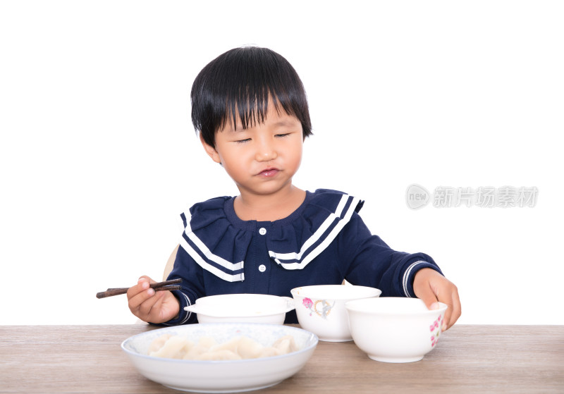 白背景前的餐桌前中国小女孩在自己吃饭