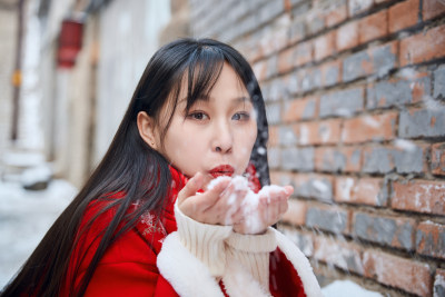 雪后在老城古巷穿着喜庆服饰的亚洲少女