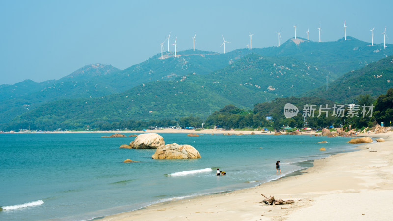 广东汕头南澳岛青澳湾海滩及远处山峦风车