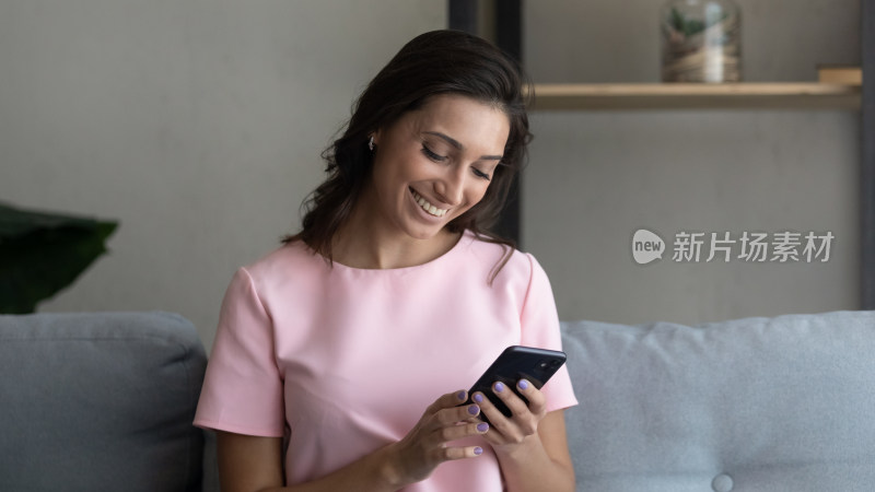 女子坐在沙发上使用手机