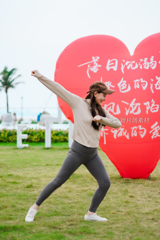 户外草地上红色心形气球前开心拍照亚洲女性