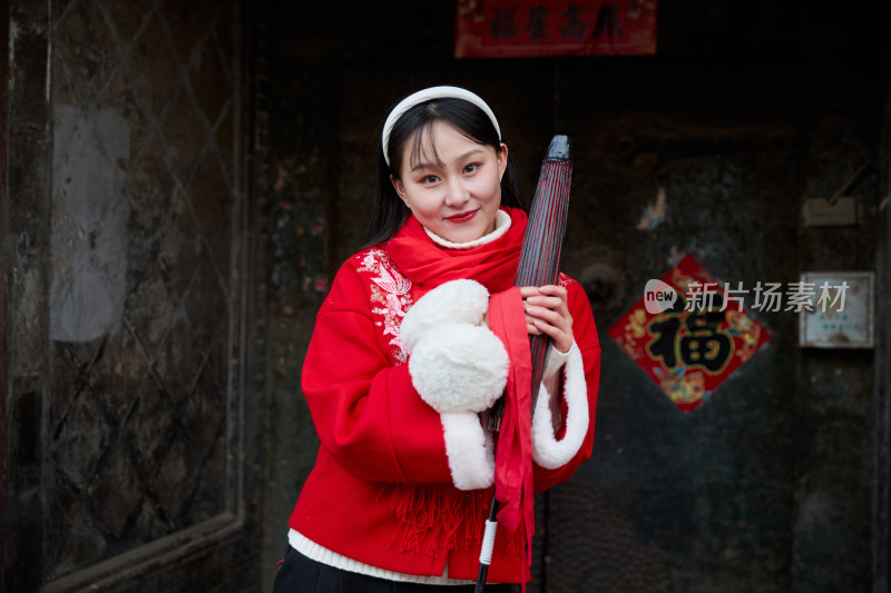 雪后在老城古巷穿着喜庆服饰的亚洲少女