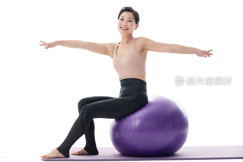 中年女性坐在瑜伽球上练习瑜伽