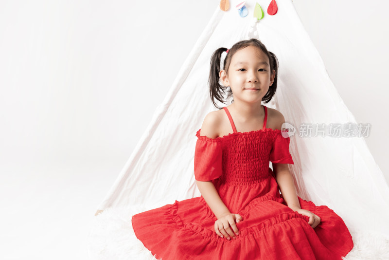 穿红色连衣裙坐在白色帐篷前的女孩