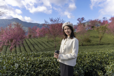 在樱花树下喝咖啡的年轻美女唯美肖像