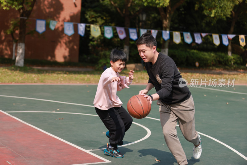 亚洲父亲和儿子在篮球场打篮球
