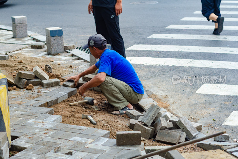 一位马路边正在铺路的建筑工人