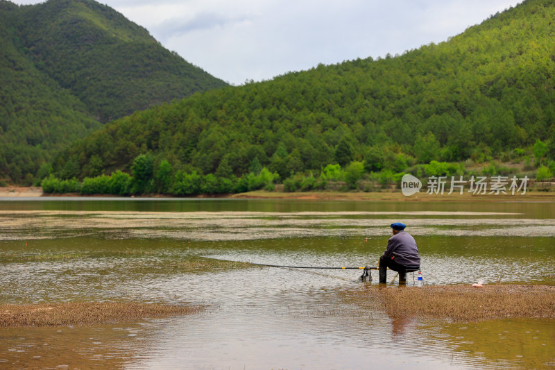 湖边小屋旁的人垂钓场景