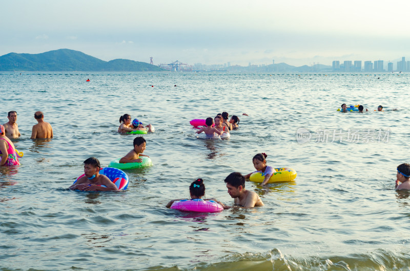 青岛汇泉湾夕阳下，海水浴场中的人们