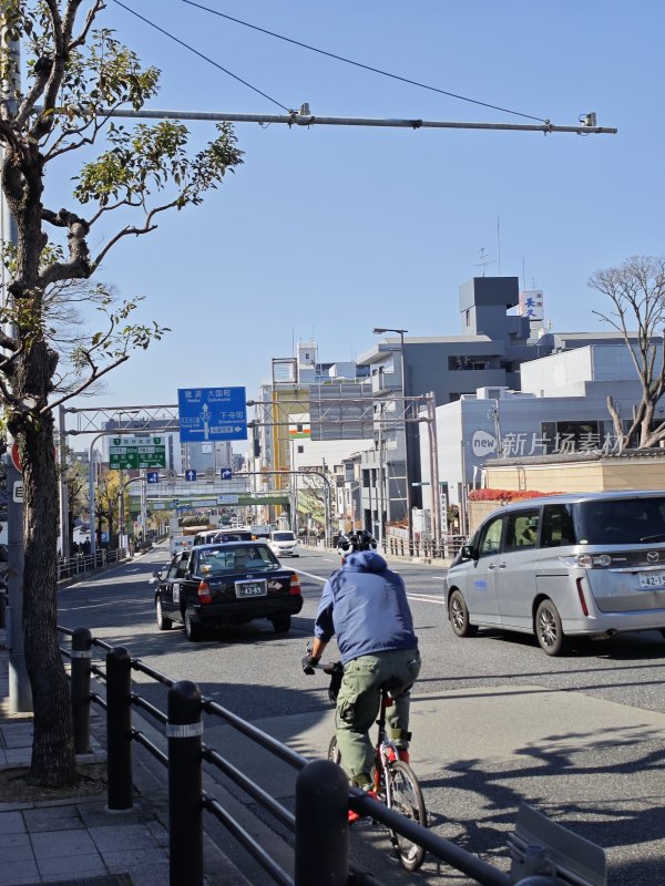 日本城市道路上骑自行车的人及行驶的车辆