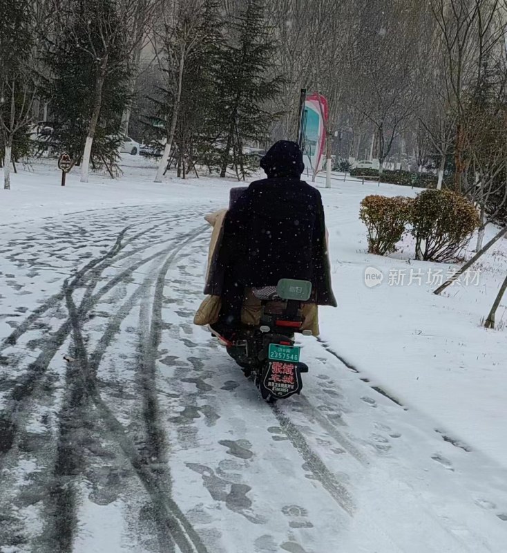 雪中骑电动车的人背影