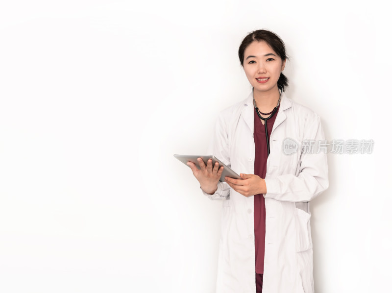 站在白色背景前使用平板电脑的中国女性医生