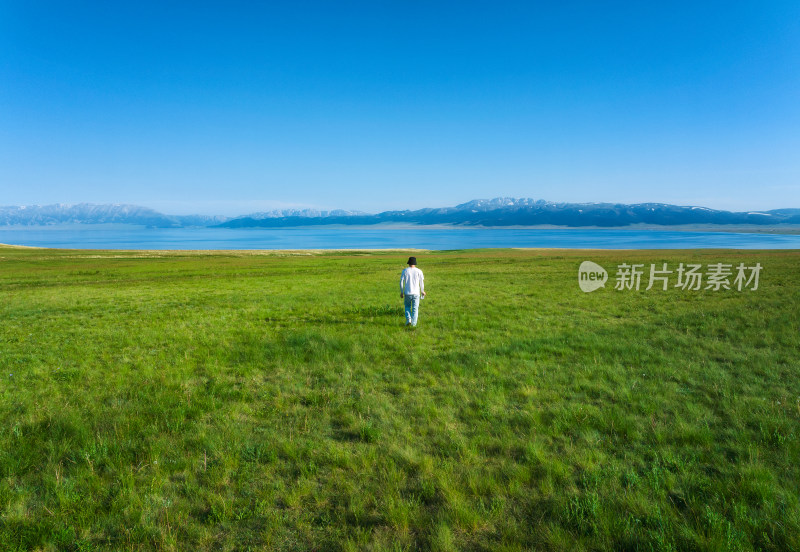 航拍男子奔跑在夏天赛里木湖畔的草地上